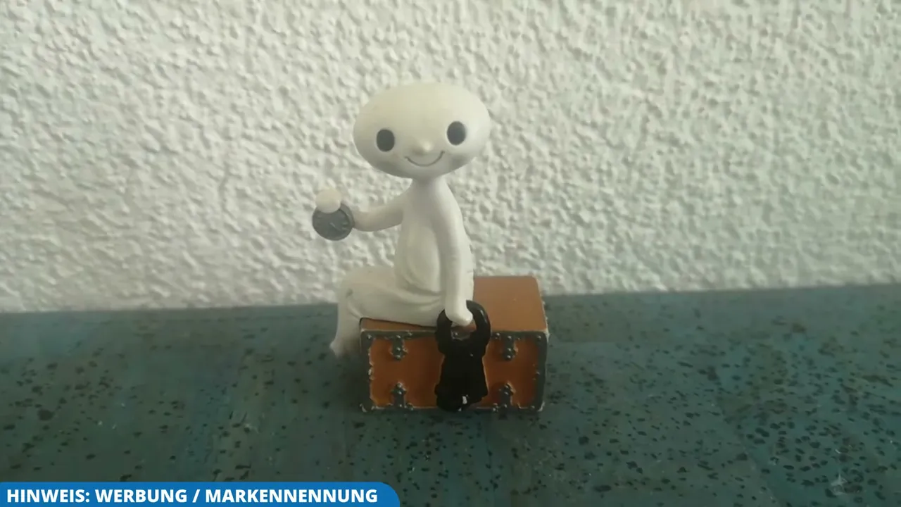 Die Tonie-Figur Das kleine Gespenst sitzt mit Schlüsselbund und Uhr auf einer liebevoll gestalteten Schatztruhe.