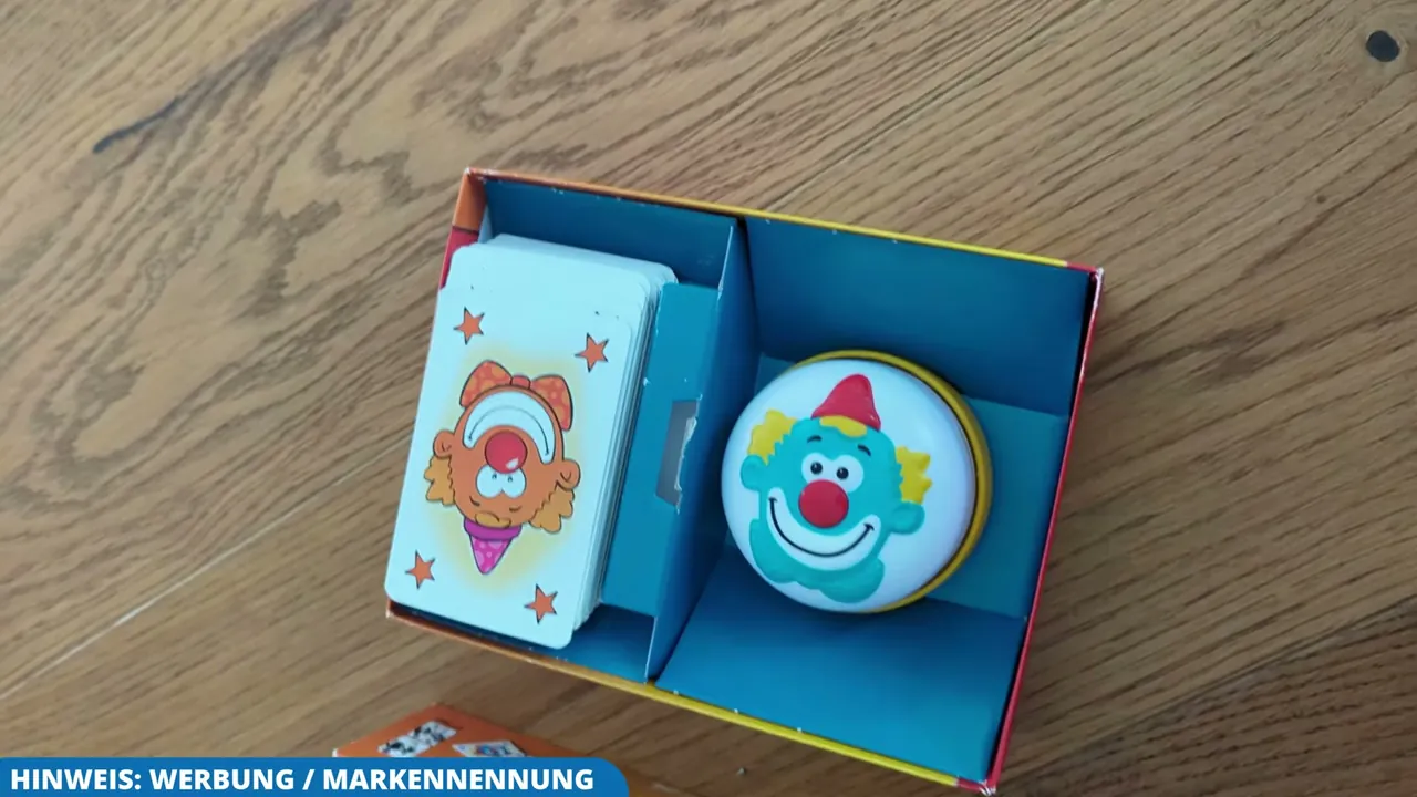 In der Schachtel von Halli Galli Junior liegen die illustrierten Spielkarten und die Glocke übersichtlich bereit.